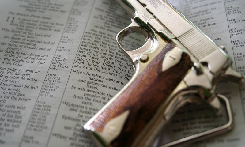 A photo of a toy gun lying on top of an open Bible.