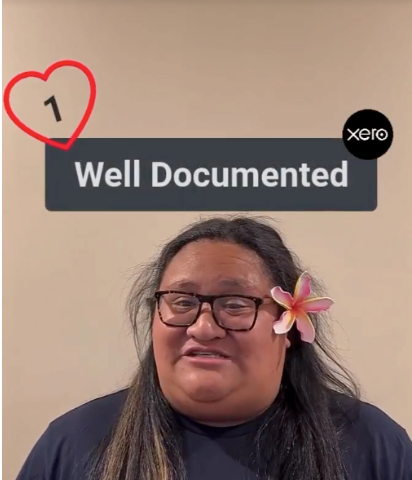 A woman with a a flower in her ear, with sign above her head saying ‘Well Documented’