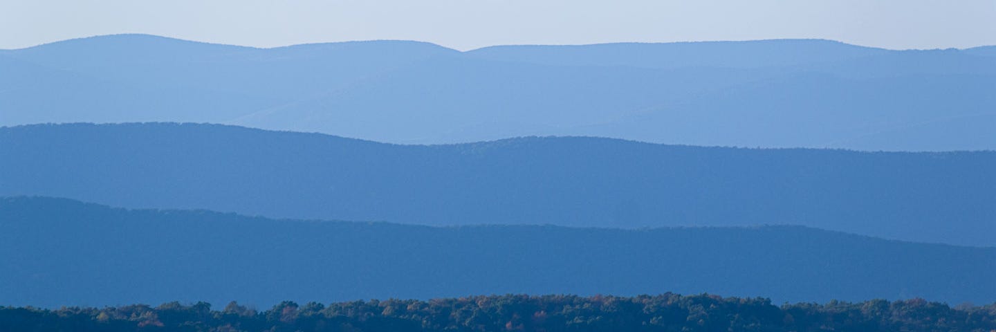 Photo of the Appalachian mountains. The mountains are layered and appear in different shades of blue from the foreground to the background.