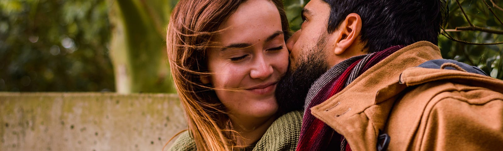 Man kisses smiling woman on check