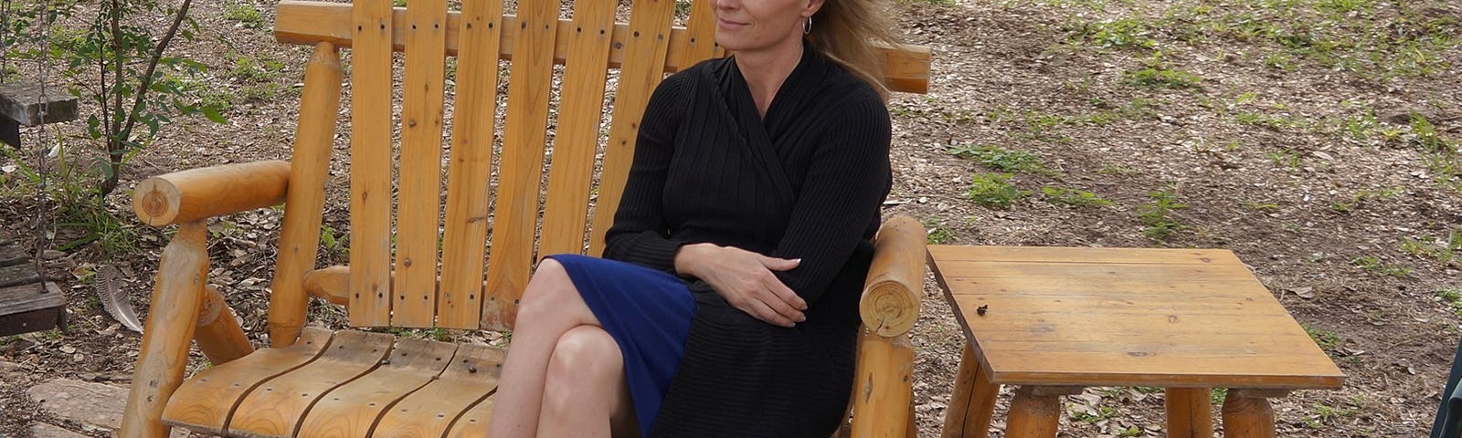 A woman sitting alone on a bench, looking at the photographer.