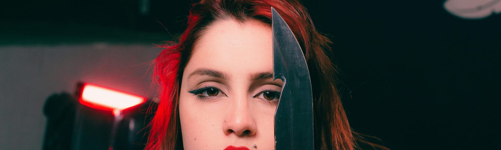 Red head woman holding knife dark background