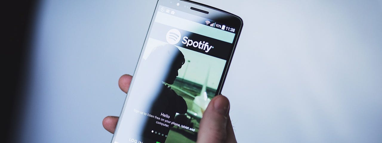 IMAGE: A hand holding a smartphone with a Spotify splash page