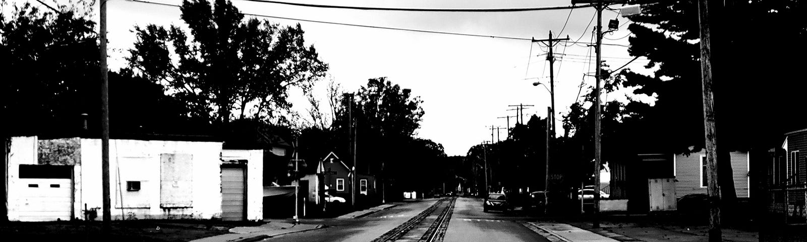 Black and white picture taken of rail tracks in the middle of small city