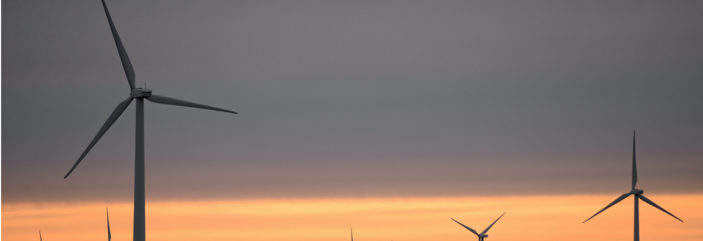 wind mills and a warm light of the sun that has just set in the background