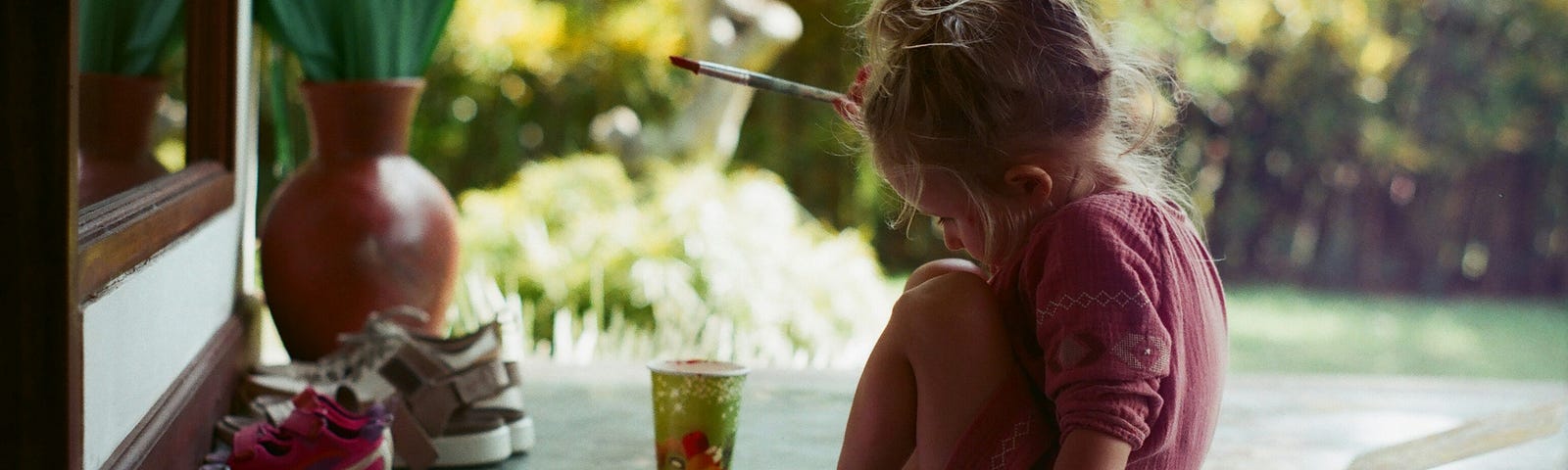 A little girl paints outside.