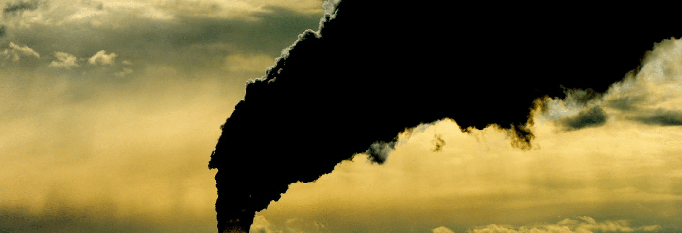 Heavy smoke from a factory chimney depicting the need for transitioning to a post carbon society