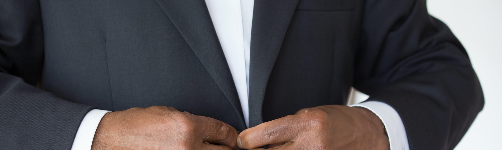 Man in a tuxedo, buttoning up his suit.