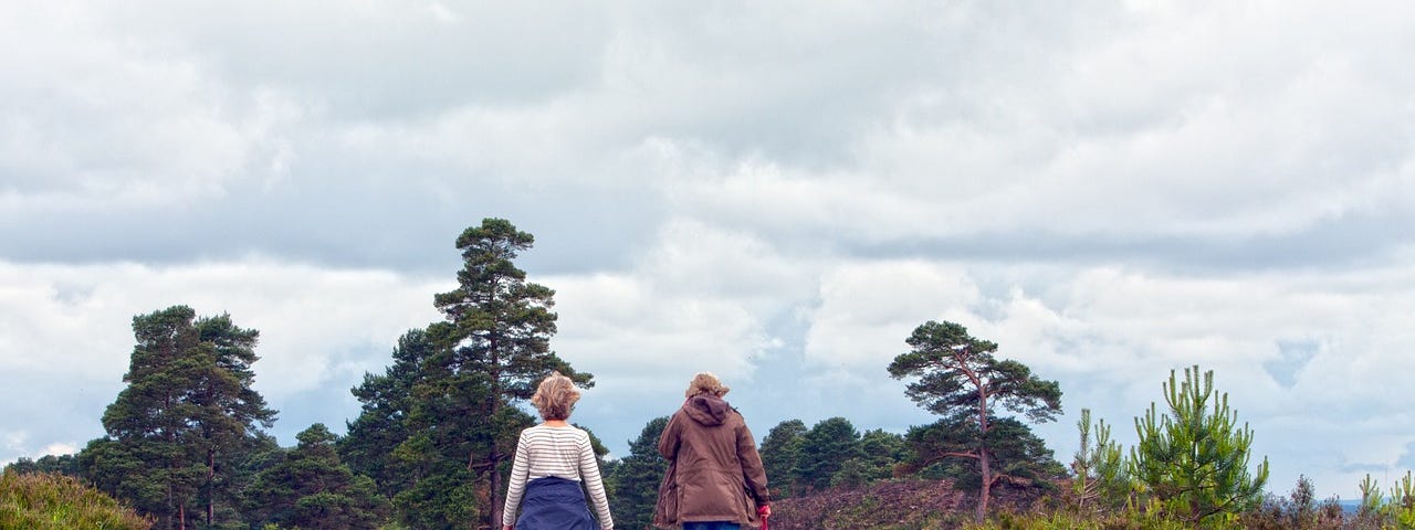 Two women walking a path up a small hill in fall.