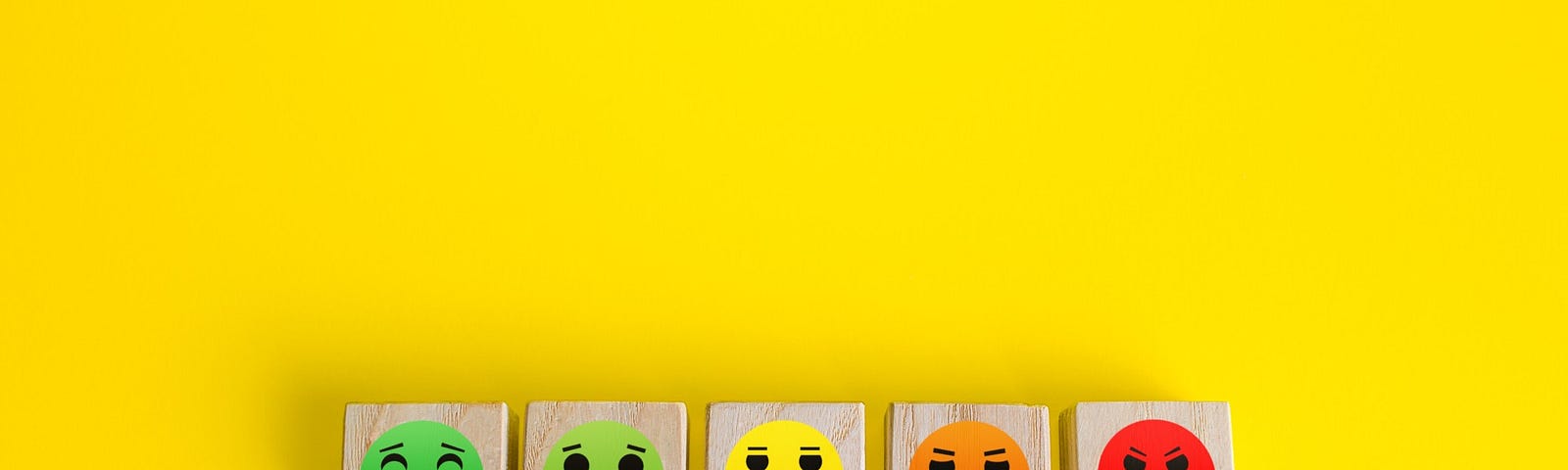 Blocks bearing a range of emotional faces (from happy to angry) sit against a yellow background.