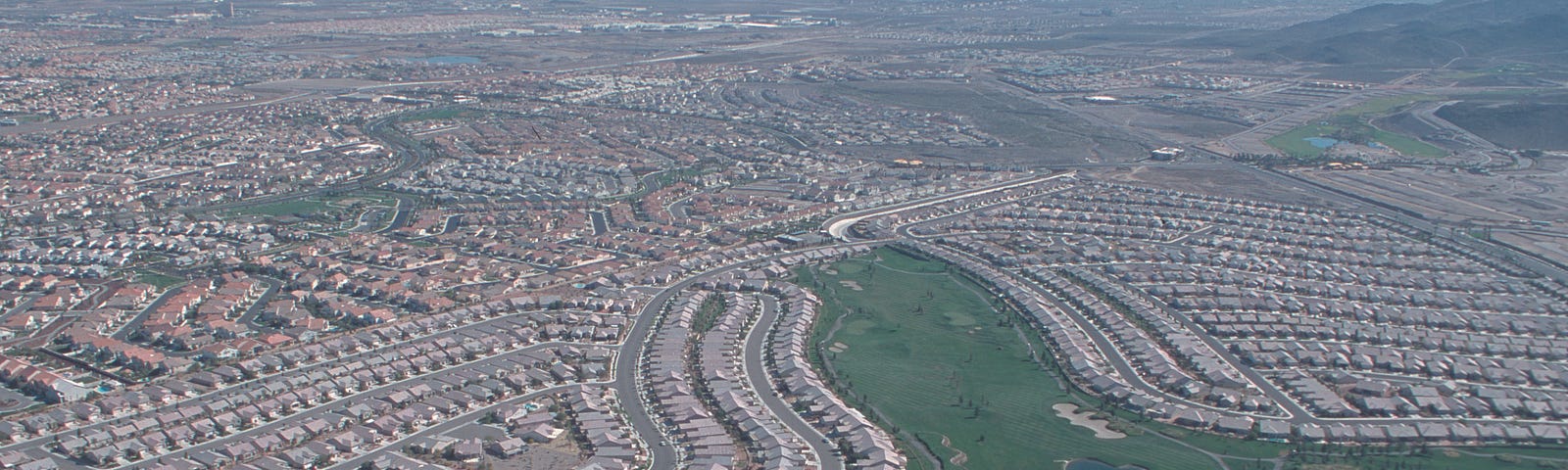 Aerieal view of sprawling suburbs. Near identical houses over and again for miles.
