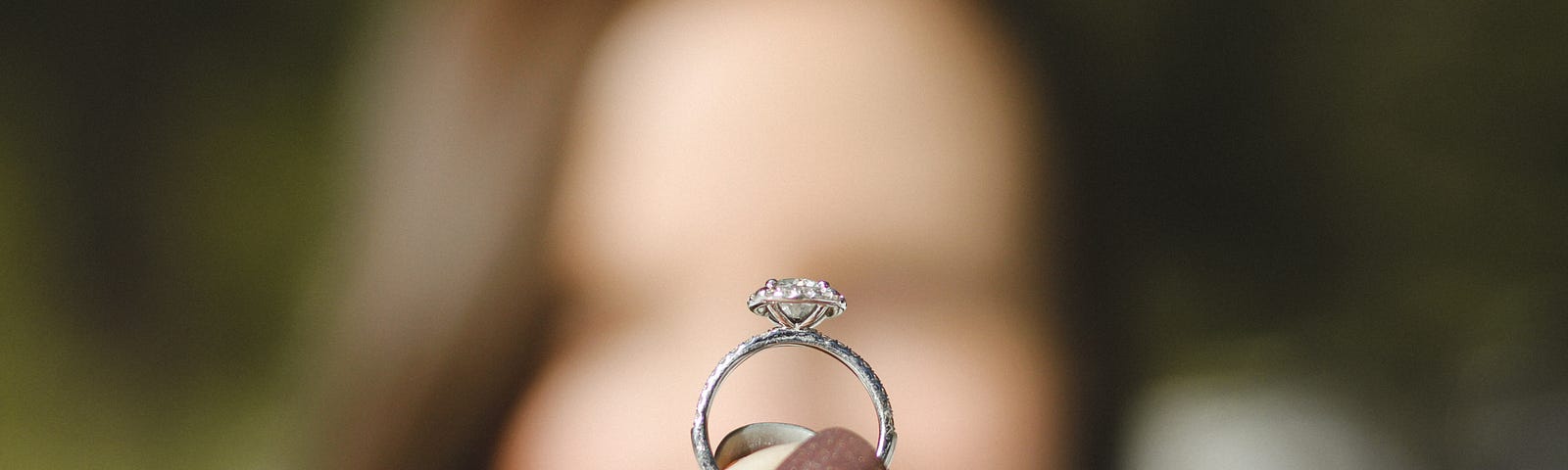 woman holding a wedding ring in the foreground
