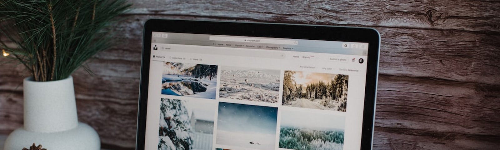 The image shows a laptop on a desk surrounded by winter and Christmas ornaments such as a candle and pine combs.