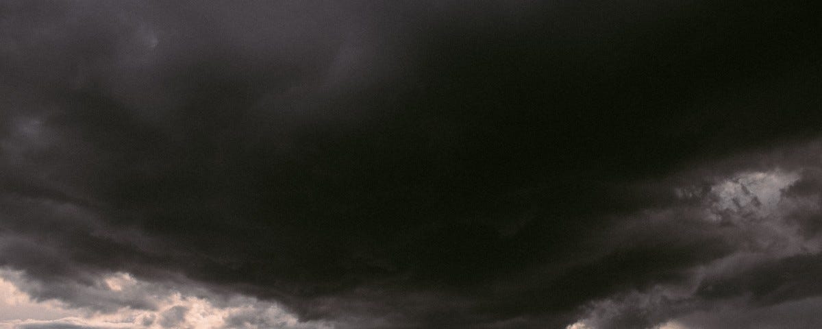 A storm rolls in over a small family gathered on a hill.