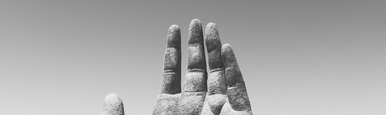 sculpture of a hand coming out of the sand