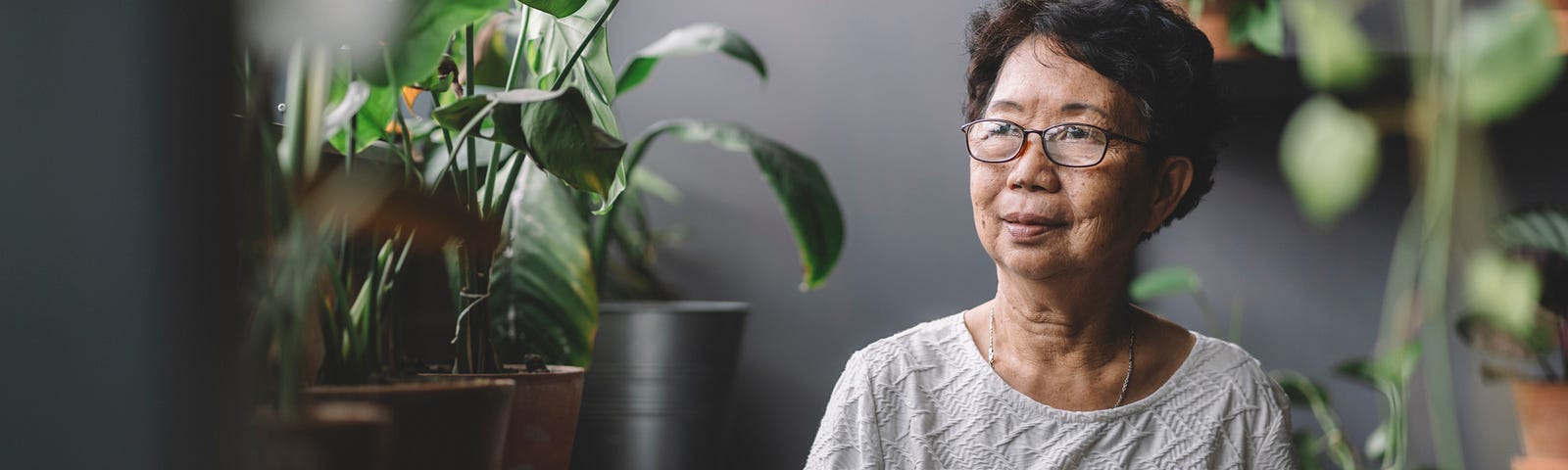 A peaceful older Chinese woman is having tea at home.