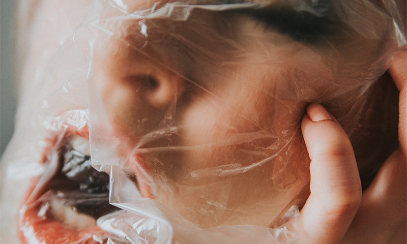 Photograph of a woman suffocating under a plastic bag