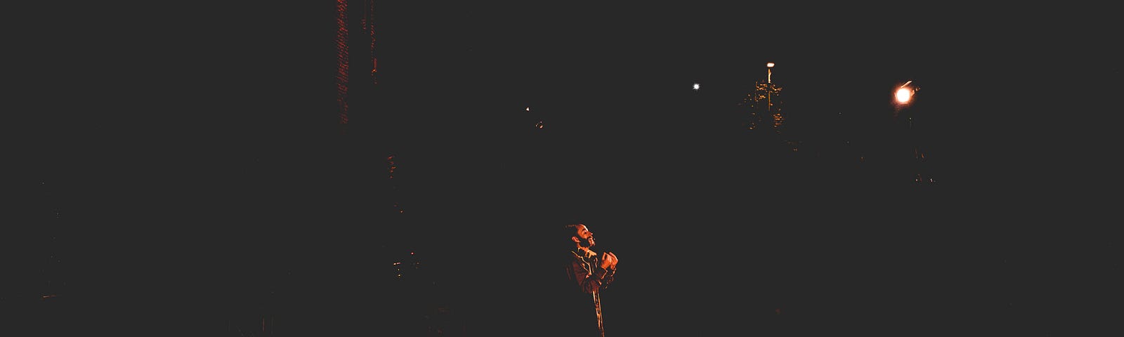 Photo of a performer on a dark stage, with a single stagelight on them.
