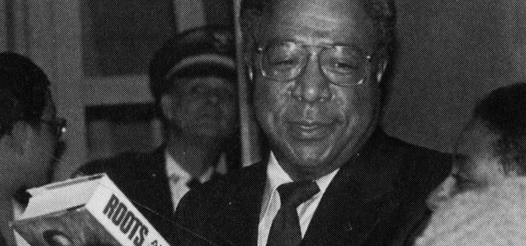 A photo of author Alex Haley holding a copy of his book, “Roots”