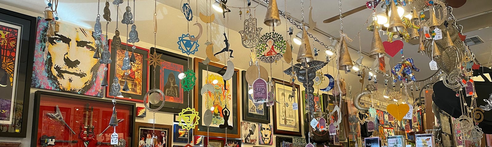 The interior of a shop, with metal decorations hanging from the ceiling, pieces of artwork on the walls, and various art pieces all around.