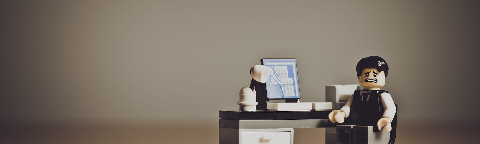 Image depicting a stressed out LEGO man sitting at his desk