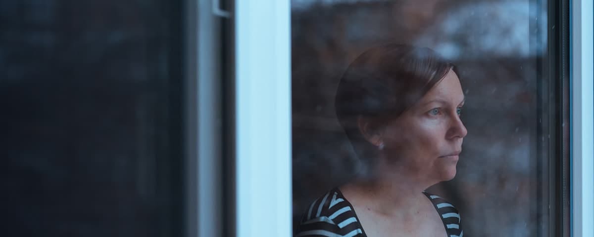 A woman with depression stares from a window. Half of all women experience depression during menopause.