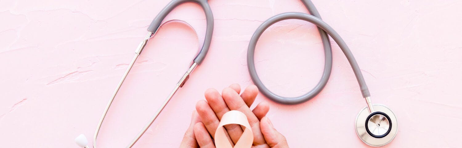 Cancer white awareness ribbon in two hands with stethoscope on pink background.
