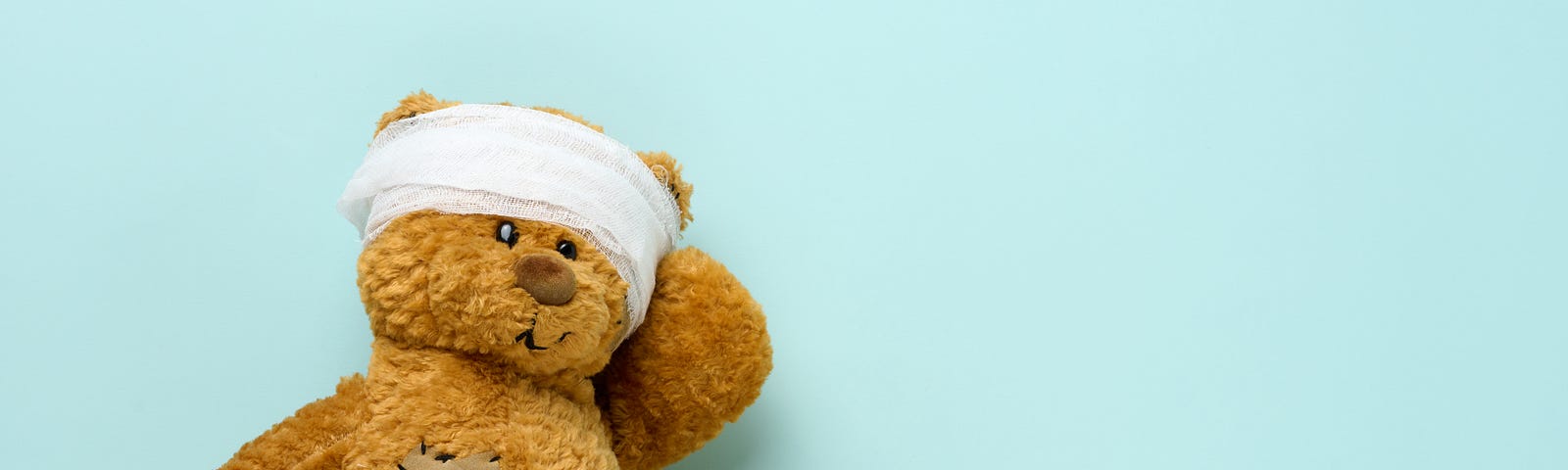 A teddy bear wears a head bandage in a sign of childhood trauma.