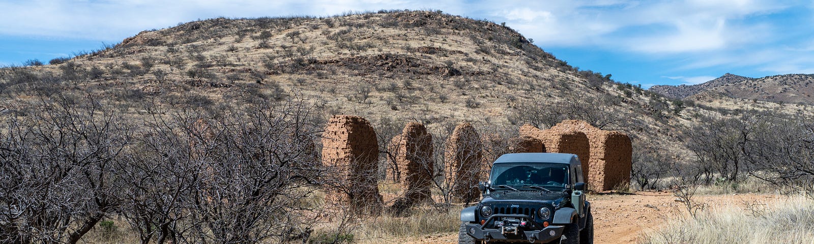 Black Jeep parked in front of adobe ruins in the southern Arizona backcountry