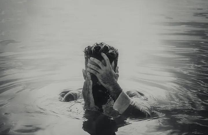 Man in water covering his face