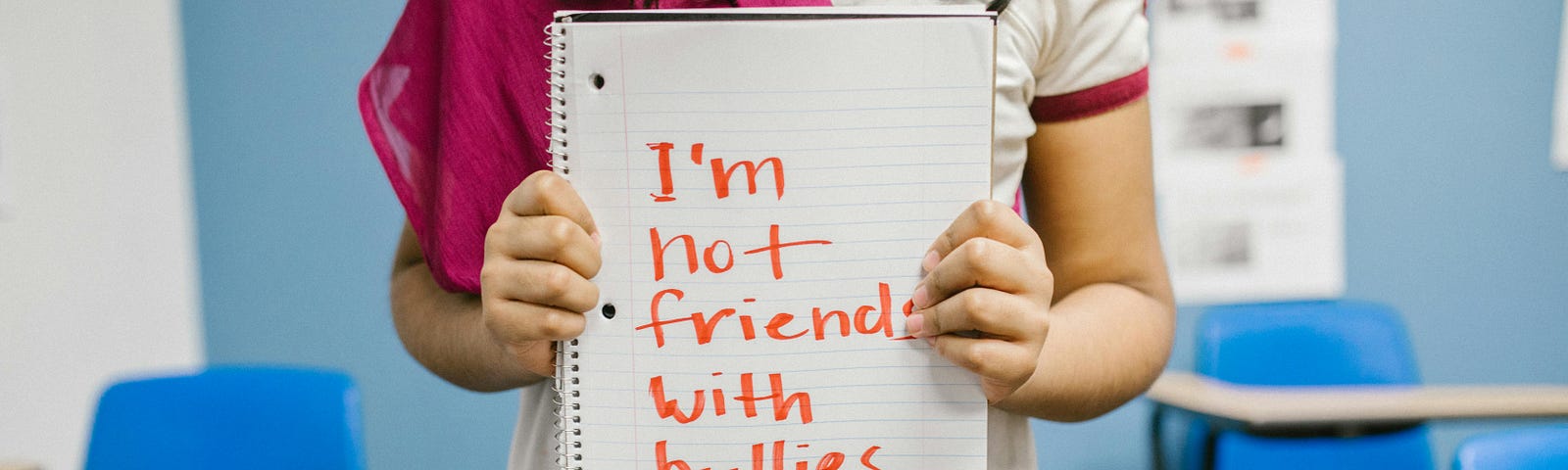 A picture of a girl holding a sign that reads, “ I am not friends with Bullies.