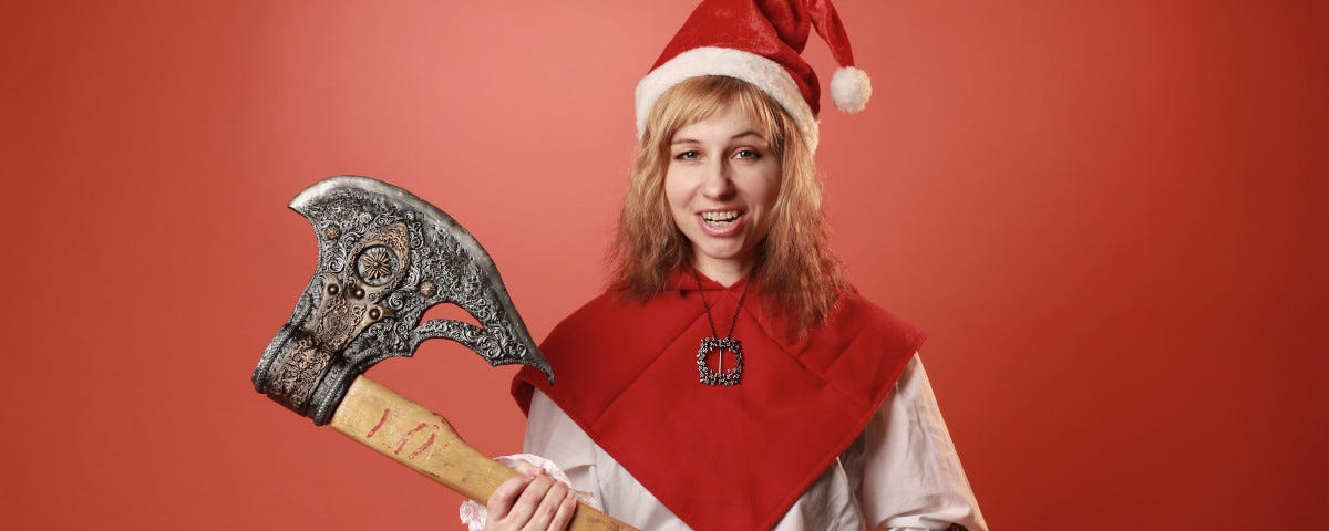 An attractive blonde woman, wearing a Santa hat, a red and white top, and tight, black leather trousers. She is wielding a headsman’s axe.