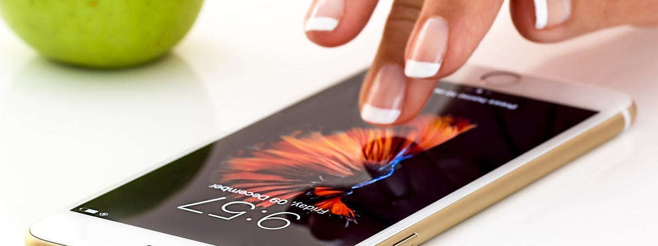 A woman’s hand tentatively reaching out through the screen of her iphone.