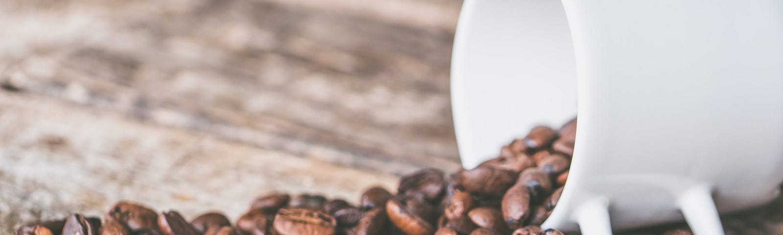 empty white coffee cup spilling coffee beans