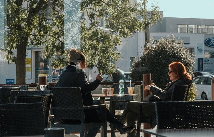 Two women are having a conversation at a coffee shop in Austria