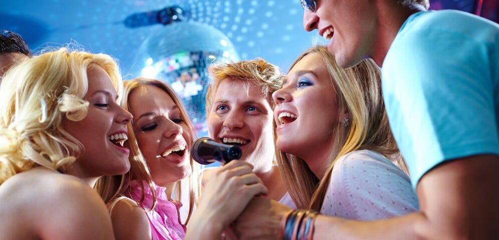 This shows a group of young people singing and dancing at a club.
