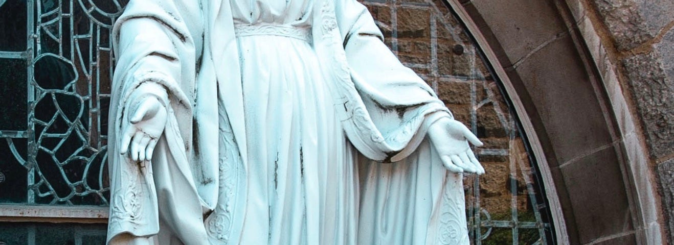 Saint Mary, with a crown of flowers, her hands are held open to welcome the lord.