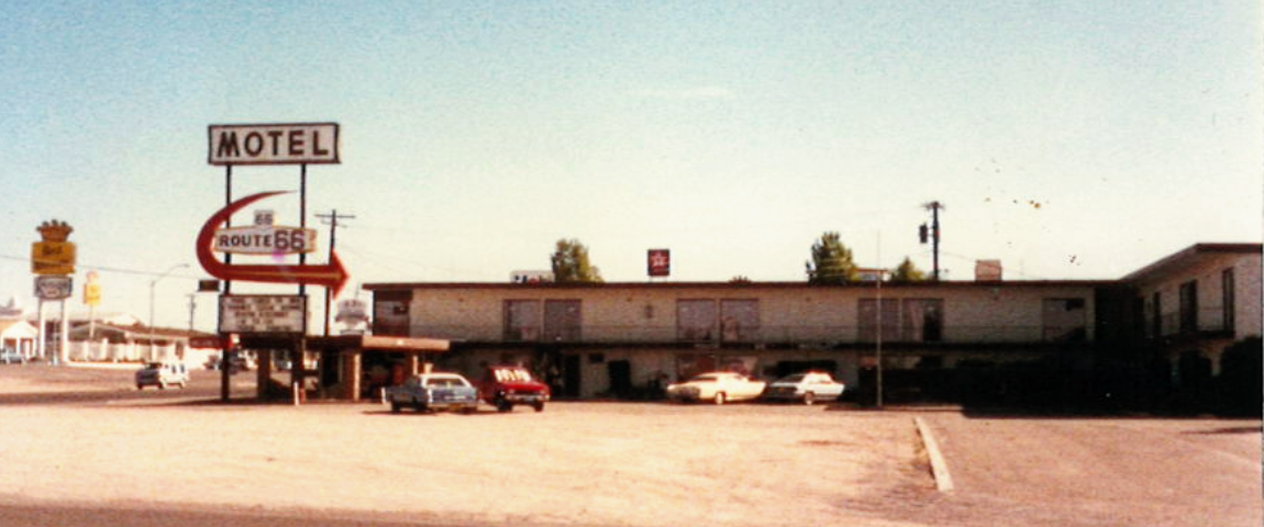 Photo of the Route 66 Motel in Kingman, Arizona taken in the summer of 1988. It was taken from afar in the dirt parking lot with motel signage in the background. The motel was a two level with sliding doors for every room facing the front.