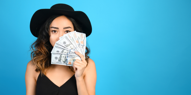 Woman in a black hat fanning money in one hand — How I Make $200 an Hour for Articles I Don’t Even Write