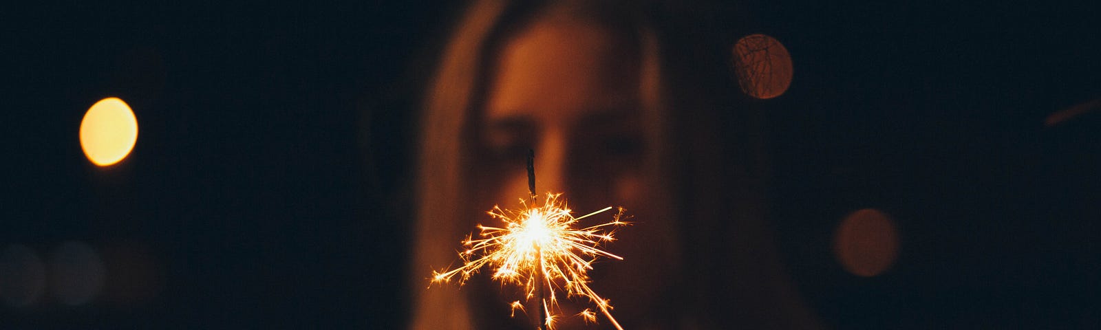 Woman holding a lit sparkler.