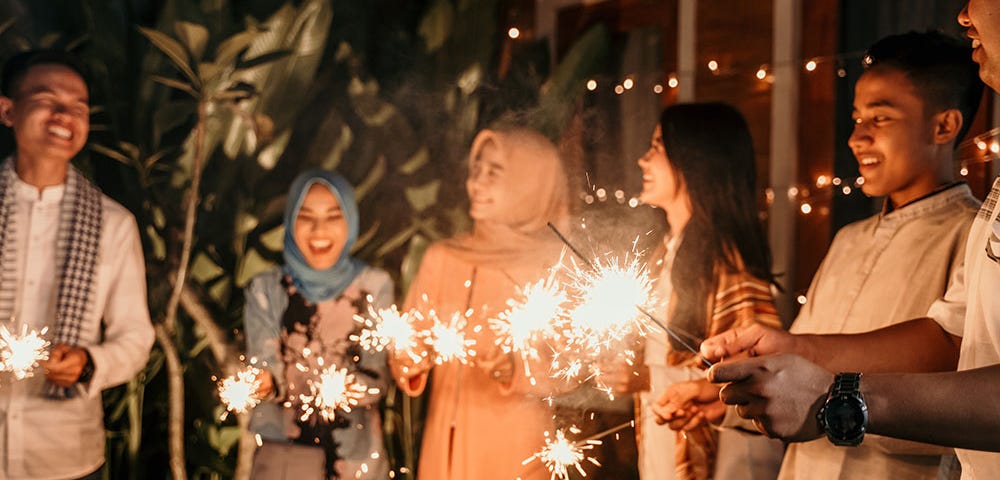 Six people in a line waving sparklers in celebration of Eid.