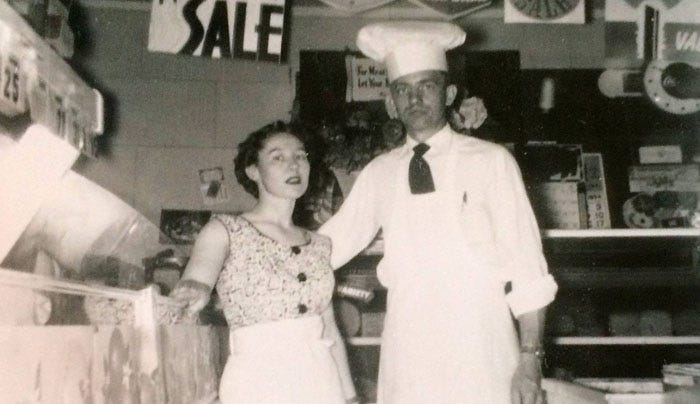 Vintage black and white photo of the owners in an old-time grocery store