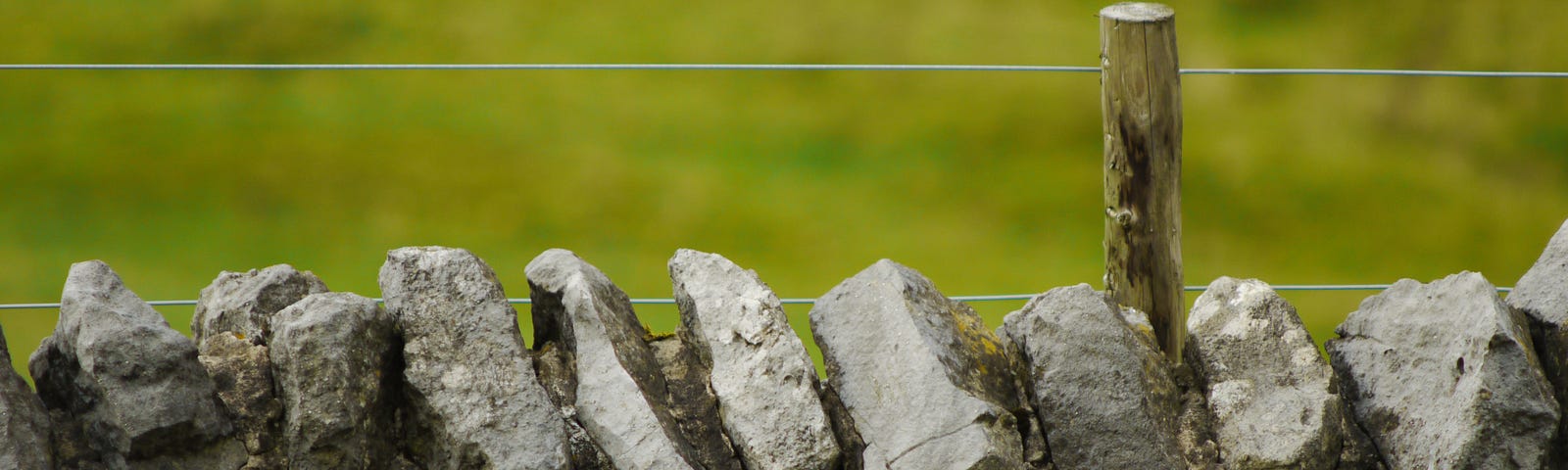 rock wall with wire strung above as in a boundary