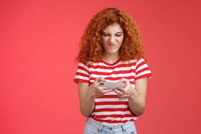 Woman female girl ginger red frowns looking at phone