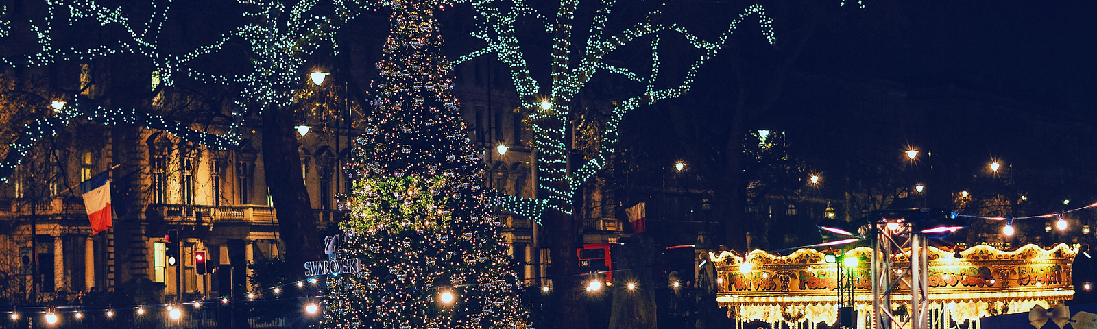 Outdoor winter scene of people skating in a rink with decorated Christmas Tree in the Center.