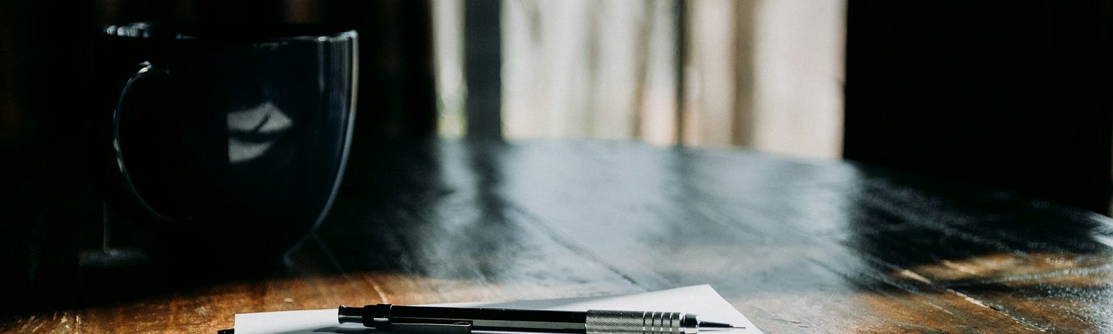 A pen sitting on top of a notebook on top of a wooden table.