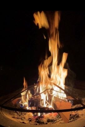A roaring fire in a backyard fire pit on a dark night.