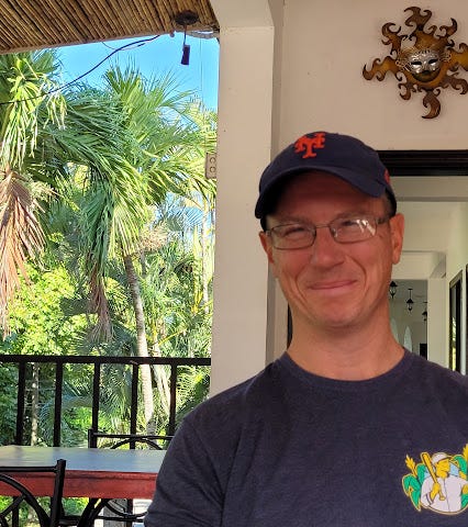 Picture of male author wearing a NY Mets hat with palm trees in the background inCosta Rica.
