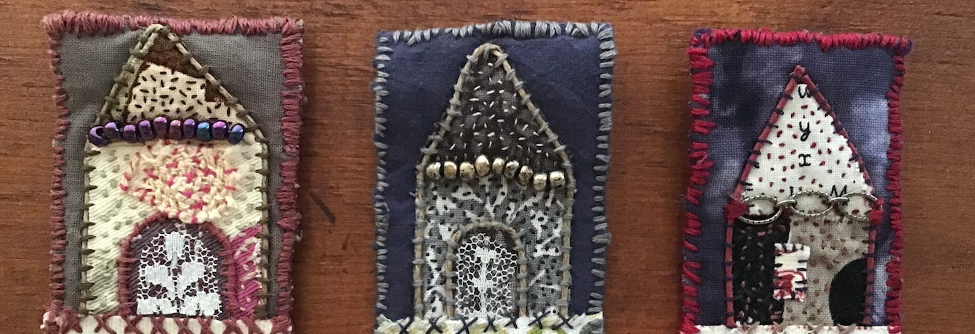 Three fabric brooches displaying miniature houses