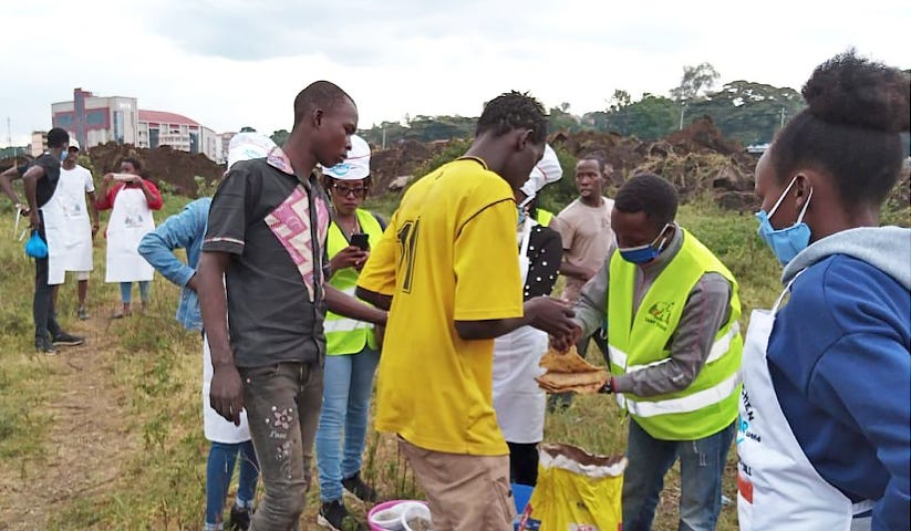 Young men line up to collect prepared food.